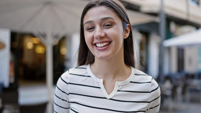 Young beautiful hispanic woman smiling confident standing at coffee shop terrace