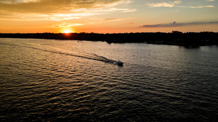 Boat cruising on lake during summer sunset