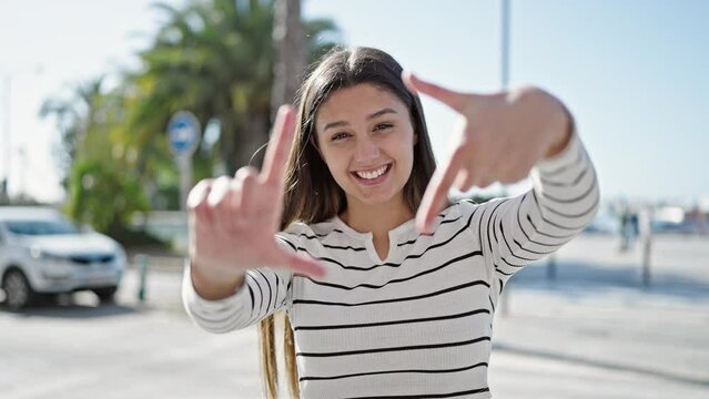 Young beautiful hispanic woman smiling confident doing frame gesture with hands at street