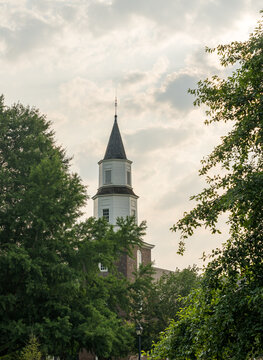 Warm sunlight at sunrise illuminates the brick and wooden tower of Bruton parish church in Williamsburg