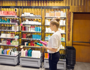 Woman buying make up at cosmetics section in store. choosing cosmetics, perfumes, creams and shampoos, Using tester.