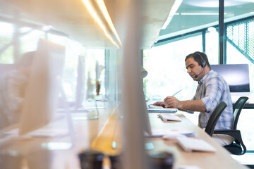 Attractive business caucasian man in headsets working with desktop computer at telemarketing customer service agents. Call center and one stop service.