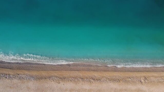 Drone top view of malachite emerald aquamarine sea water and sandy beach