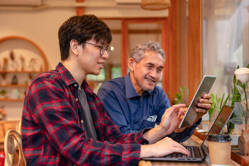 two businessmen casual working at coffee bar,a young man sitting and discussing business plan with senior over laptop and tablet computer