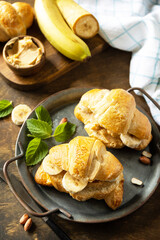 Healthy food dessert concept. French pastry. Tasty freshly baked croissants with peanut butter and banana on a rustic background.