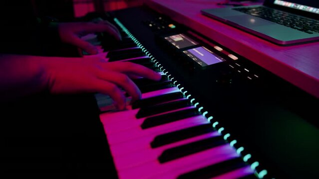professional recording studio sound engineer or music producer musician pressing synthesizer keys red neon light