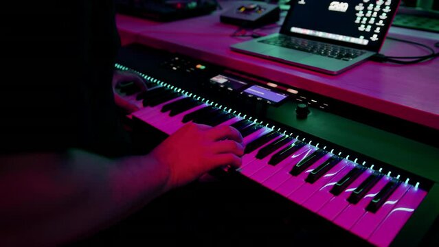 professional recording studio sound engineer or music producer musician pressing synthesizer keys red neon light