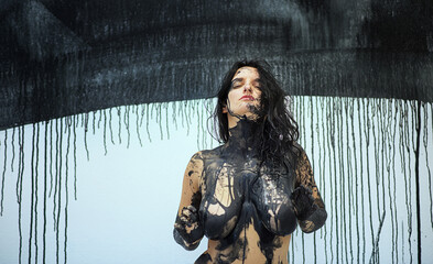 Portrait, hands and torso of a naked sensual woman full of feeling, emotion in black color painted...