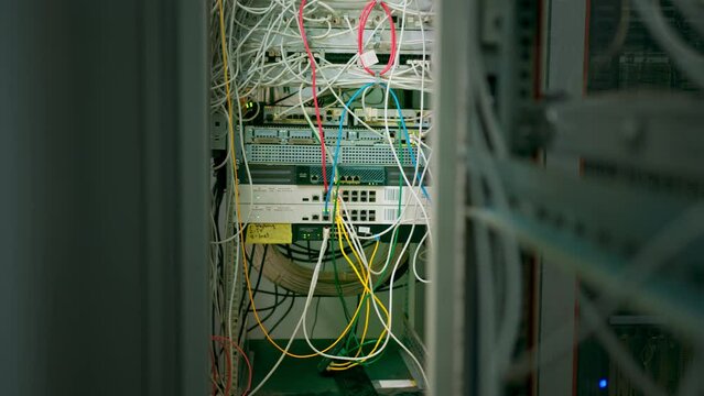 a bunch of patch network cables sorted in a rack cabinet leading from a patch panel in a server rack in a data center room internet cloud storage
