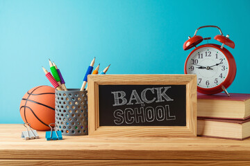 Back to school background with pencils, basketball ball, books and chalkboard on wooden table over...