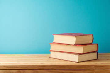 Books on wooden table over blue background. Back to school concept