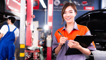 Portrait of Beautiful Asian young female mechanic in uniform with smile. Professional inspects check engine in Auto garage. Auto repair service and maintenance Concept.
