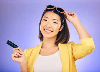 Credit card, shopping portrait and woman in sunglasses, retail banking and finance, e commerce or payment. Happy customer, fashion model or asian person for debit pay on studio purple background