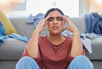 Headache, stress and woman with depression from laundry in a living room, exhausted and unhappy in her home. Anxiety, migraine and female person frustrated with household, task or spring cleaning