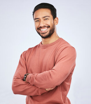 Portrait, smile and Asian man with arms crossed, casual fashion and confident guy against a white studio background. Face, male person and Japanese model with happiness, aesthetic and stylish outfit