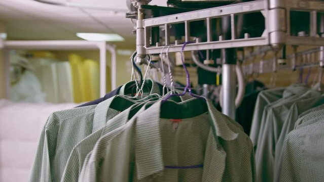 industrial laundry in hotel clean shirts of employees and guests sorted after washing hung scrolled on conveyors concept of cleanliness and hospitality