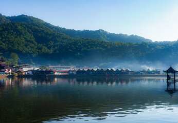 A view of a village with morning mist and surrounded by mountains.