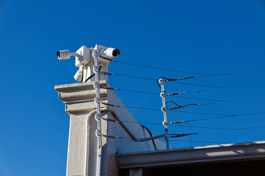 White CCTV cameras on a wall against blue skies in Worcester, Western Cape, South Africa.