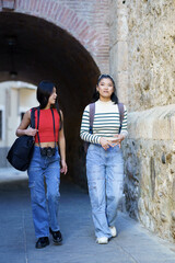 Asian girls friends walking with bags together in street