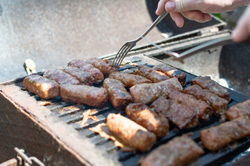 Mititei. Turn the mititei on the grill with a fork. Mititei or mici, typical romanian and moldavian food grilled ground meat rolls made from a mixture of beef and lamb and spices. Selective focus