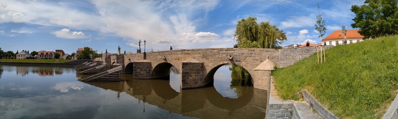 Fototapeta premium The Pisek Stone Bridge is the oldest preserved early Gothic bridge in the Czech Republic.Pisek town in south Bohemia,historical bridge over Otava river,scenic panorama landscape view