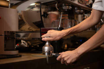 Fototapeta na wymiar Close-up of barista hands using Portafilter for making espresso.