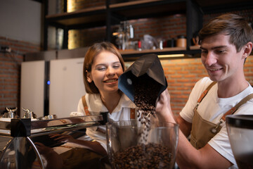 The barista fills the coffee grinder with roasted coffee beans. to prepare coffee for customers
