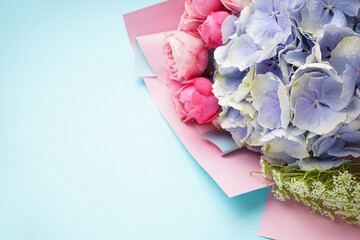 Bouquet of peony roses with hydrangea on a blue background, space for text. Top view.
