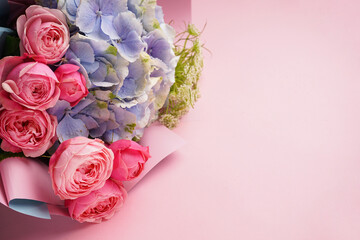 Bouquet of peony roses with hydrangea on a pink background, space for text. Top view.