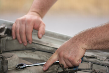 repairing a car, the hands of a mechanic tigheten a nut with a metal wrench