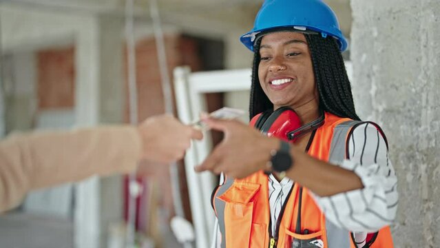 African american woman builder receiving dollars shake hands at construction site
