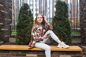 young woman sitting on a street bench in the city with a phone