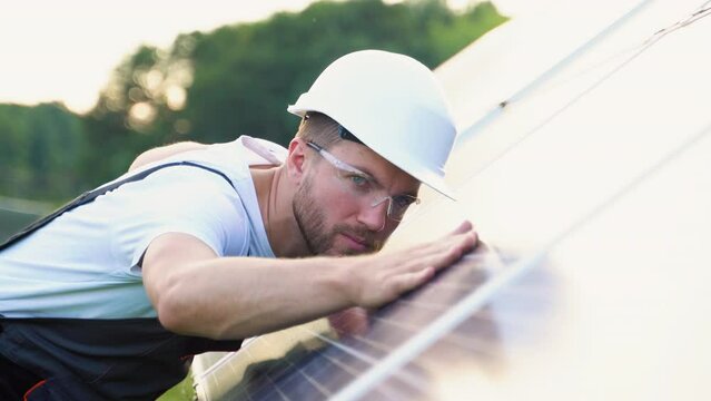Close up of an young engineer hand is checking an operation of sun and cleanliness of photovoltaic solar panels on a sunset