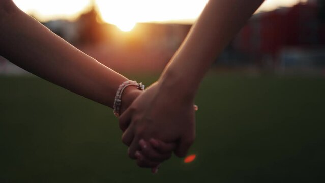 Couple in love holding hands on city background. Close up of two girl's hands meeting on a city street. Unidentified two female friends touching hands outdoors. LGBT