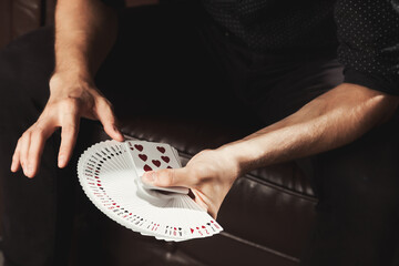 Close-up clever male hands of magician with gambling cards. Gambler man showing performing fan of cards. Concept of magic, performance, circus, gambling, casino, poker game, show. Copy ad text space - obrazy, fototapety, plakaty
