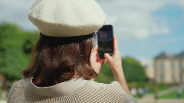 Young girl taking a photo of the garden at the Rodin Museum on her phone