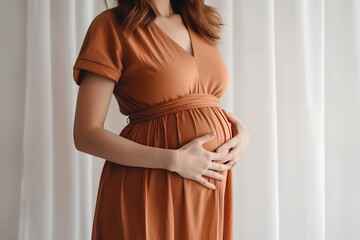 Pregnant woman in dress holds hands on belly on a white background. Close up cropped of pregnant woman in green dress touching caressing belly, expecting first baby child