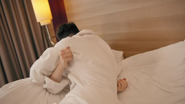 portrait young couple on honeymoon in hotel room lying on bed in white robes kissing happy lovers travel concept