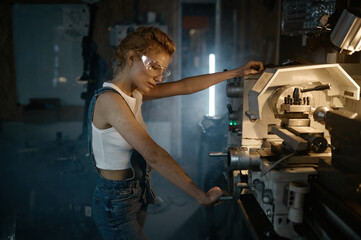 Young blond woman mechanical engineer working on lathe machine