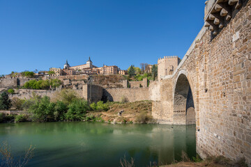 Fototapeta premium Toledo Skyline with Alcazar of Toledo, Alcantara Bridge and Tagus River - Toledo, Spain