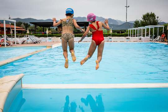 rear view of two girls jumping in the water in the pool