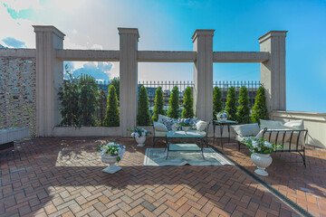 a chic terrace of a country house with wrought iron furniture, vases with flowers and columns on a bright summer sunny day
