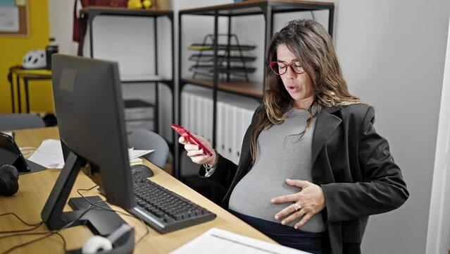 Young pregnant woman business worker using smartphone and computer suffering for belly pain at office