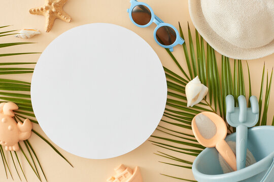 Seashore getaway idea for children. Top view photo of eyeglasses, sun hat, beach toys, tropical leaves, seashells, starfish on pastel beige background with blank circle for advert or message