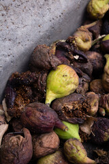 Vertical photo. Rotten unripe green and fruit figs on the pavement. The concept of bad food, garbage, harvest, lean year. Southern fruit. Georgian farm products. Bad logistics.