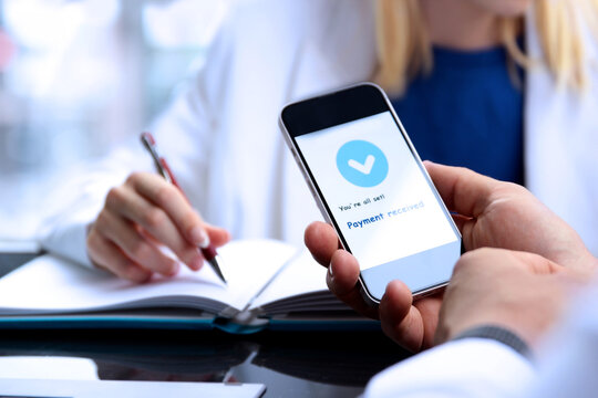 Business persons working  together in the office. Businessman showing a mobile phone with statement that payment received.