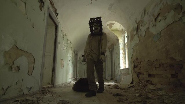 Ghost of maniac with cage on his head dragging dead body down corridor of asylum