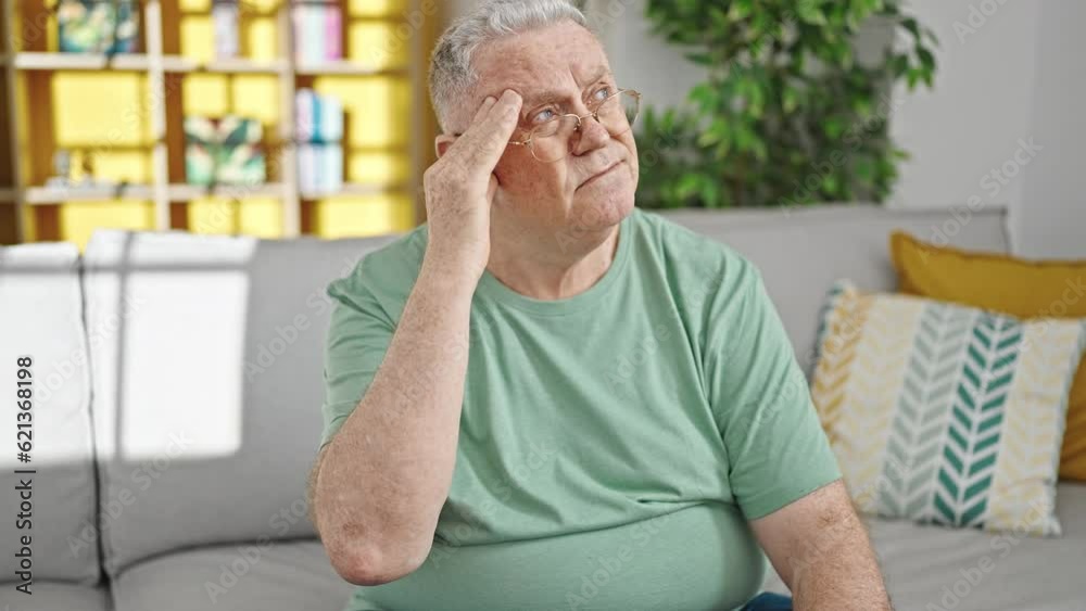 Poster middle age grey-haired man suffering for headache sitting on sofa at home