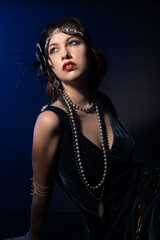 Studio portrait of a caucasian model wearing 1920s retro fashion. She is dressed as a flapper with...