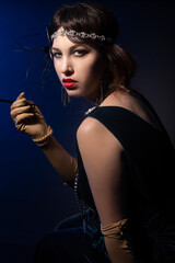 Studio portrait of a caucasian model wearing 1920s retro fashion. She is dressed as a flapper with...